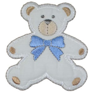 May include: White embroidered teddy bear with a blue bow. The bear has brown eyes and a brown nose.