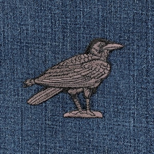 Könnte beinhalten: Ein gestickter Rabe in Schwarzweiß auf einem blauen Jeansstoff.