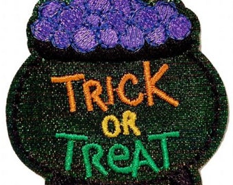 May include: A green cauldron with a purple cauldron full of sweets on top. The cauldron has the text "Trick or Treat" in orange, yellow, and green.