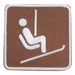 May include: A brown square patch with a white outline. The patch features a white silhouette of a person sitting on a ski lift.