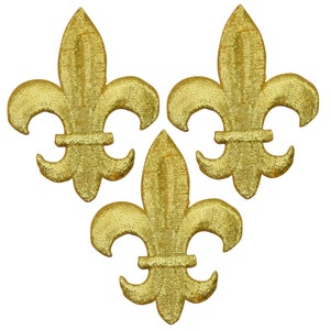 May include: Three gold fleur-de-lis patches arranged in a triangular pattern. Each patch has a detailed embroidered design with a metallic sheen. The patches are set against a plain white background.