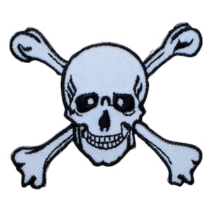 May include: An embroidered patch featuring a white skull and crossbones design with black stitching details. The skull has hollow eye sockets, a triangular nose cavity, and a visible row of teeth, all outlined in a bold black thread border.