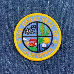 May include: A blue and yellow embroidered patch with the words "The Great Seal of California" and images of a cable car, a palm tree, a bear, and a redwood tree.