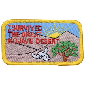 Op de afbeelding: Geborduurde patch met een gele rand met een woestijnlandschap. De patch bevat de tekst "I SURVIVED THE GREAT MOJAVE DESERT" in het rood, een zon, bergen, een boom en een schedel.