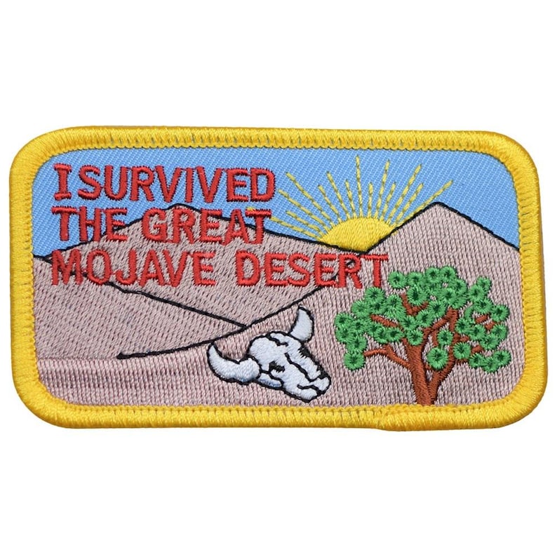 Op de afbeelding: Geborduurde patch met een gele rand met een woestijnlandschap. De patch bevat de tekst "I SURVIVED THE GREAT MOJAVE DESERT" in het rood, een zon, bergen, een boom en een schedel.