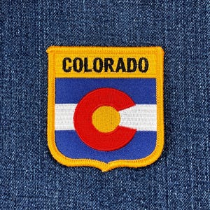 May include: Embroidered patch featuring the Colorado state flag design. The patch has a yellow border and the word "COLORADO" at the top. The flag design includes blue and white stripes, and a red and yellow circular emblem.