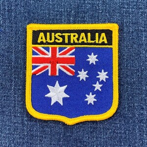 May include: A yellow and black embroidered patch with the word "AUSTRALIA" in yellow letters and the Australian flag. The flag is blue with a white Southern Cross constellation and a red Union Jack in the upper left corner.