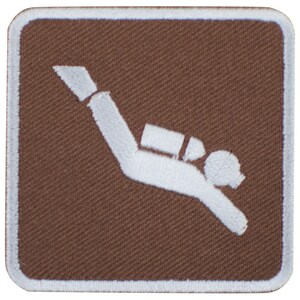 May include: A brown square patch with a white embroidered scuba diver icon. The diver is wearing a tank and has a diving mask.