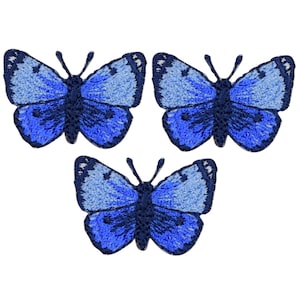 May include: Three blue embroidered butterfly patches. The butterflies have dark blue wings with a lighter blue gradient.