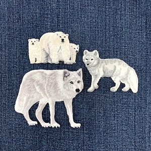 May include: Three embroidered patches featuring arctic animals. One patch shows a white polar bear standing between two smaller polar bear cubs. A second patch depicts a white arctic fox standing in profile. All patches have white fur details.