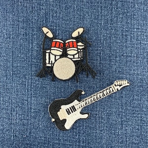 May include: Two embroidered patches featuring musical instruments. One patch depicts a drum kit with red and white drums and black hardware. The second patch shows an electric guitar with a black body, white pickguard, and a long neck with frets.