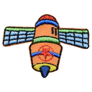 May include: An embroidered patch depicting a cartoon satellite with a red star on the side. The satellite is orange, blue, green, and black.