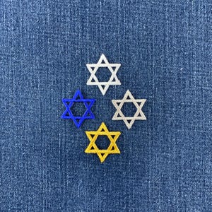 May include: Four embroidered Star of David patches arranged in a diamond pattern. The top patch is white, the left is blue, the right is light grey, and the bottom is yellow. Each six-pointed star features a stitched border and a hollow centre.