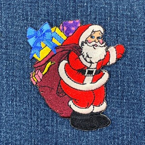 May include: Embroidered iron-on patch featuring a red-suited Santa Claus carrying a bag of gifts. The bag is filled with wrapped presents, including a blue and yellow box with a blue bow. Santa has a white beard and a white fur trim on his suit.