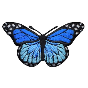 May include: A blue and white embroidered butterfly patch with black outlines. The butterfly has a gradient of blue from dark to light.