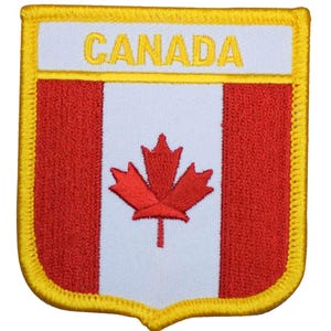 May include: A rectangular embroidered patch featuring the Canadian flag design with a red maple leaf centered on a white vertical stripe between two red stripes. The word CANADA is stitched in yellow on a white top bar with a yellow border.