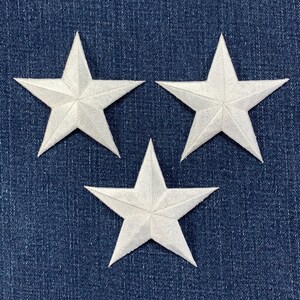 Könnte beinhalten: Drei weiße Filzsterne auf einem blauen Jeansstoff.