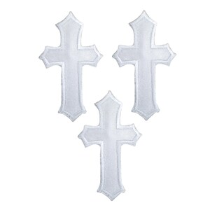 May include: Three white embroidered crosses with a decorative, pointed design. The crosses are arranged in a triangular pattern against a white background. The embroidery has a textured appearance.