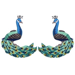 May include: Two embroidered peacock patches. Each patch features a peacock with a blue head and neck, teal and green body, and a fan of teal feathers with yellow and blue accents. The patches are on a white background.