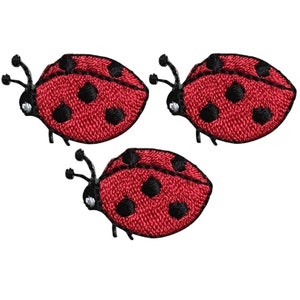 Könnte beinhalten: Drei rote und schwarze Bügeleisen-Aufnäher in Form von Marienkäfern. Die Marienkäfer haben schwarze Punkte und sind gestickt.