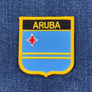 May include: A yellow and blue embroidered patch with the word "ARUBA" in yellow letters on a black background. The patch features the flag of Aruba, which includes a blue background with two yellow stripes and a red star.