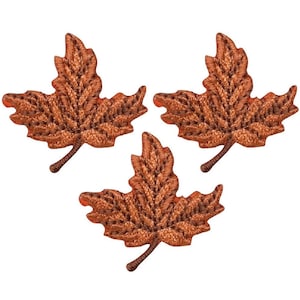 May include: Three brown embroidered maple leaf patches. The leaves are detailed with a brown outline and a darker brown fill.