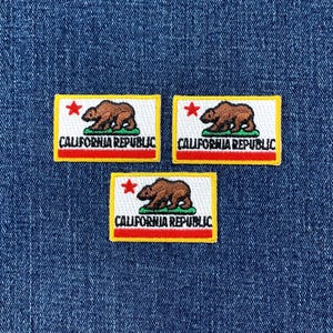 May include: Three rectangular patches featuring the California state flag. Each patch has a white background with a brown bear, a red star, and the words "CALIFORNIA REPUBLIC". The patches have a yellow border and a red stripe at the bottom.