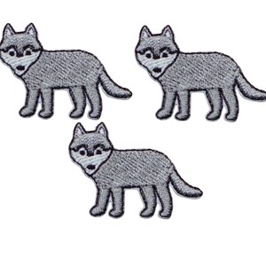 May include: Three gray embroidered iron-on patches of wolves. Each patch is approximately 1.5 inches tall and 2.5 inches wide.