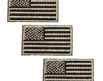 May include: Three embroidered American flag patches in a camouflage pattern. The patches are beige with black stitching and are approximately 2 inches by 3 inches.