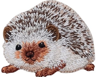 以下が含まれることがあります： かわいい顔をした茶色と白の刺繍パッチのハリネズミ。ハリネズミは、とげがはっきりと見えるように丸まってボール状になっています。