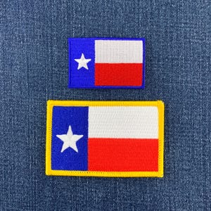 Könnte beinhalten: Zwei rechteckige gestickte Aufnäher mit dem Design der Flagge des Bundesstaates Texas. Jeder Aufnäher zeigt einen vertikalen blauen Streifen mit einem weißen Stern, gefolgt von horizontalen weißen und roten Streifen. Der untere Aufnäher hat einen gelben Rand.
