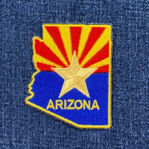 May include: Embroidered patch in the shape of Arizona, featuring a gold star over a blue field, with red and yellow rays in the upper section. The word "ARIZONA" is embroidered in gold.
