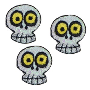 May include: Three white skull iron-on patches with black outlines and yellow eyes. The skulls have a glittery finish.