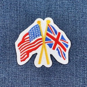 May include: Embroidered patch featuring the flags of the United States and the United Kingdom. The American flag has red and white stripes with a blue field of stars. The British flag has a red cross on a blue background. The flags are on yellow poles.