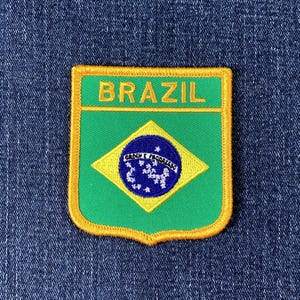Peut inclure: Écusson brodé représentant le drapeau brésilien. Le patch a un fond vert avec un losange jaune et un cercle bleu contenant des étoiles. Le mot "BRAZIL" est brodé en jaune en haut.