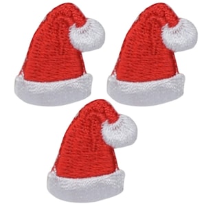 Könnte beinhalten: Drei rote und weiße Weihnachtsmützen mit weißen Bommeln. Die Mützen sind gestickt und etwa 2,5 cm groß.
