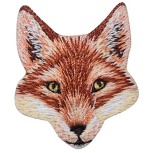 May include: Embroidered patch of a fox head. The patch is detailed with brown, orange, and cream threads, with yellow eyes and a black nose. The fox's face is centered, with its ears pointed upwards, creating a striking design.