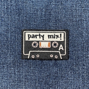May include: A black and white cassette tape patch with the words "party mix!" in white lettering. The patch is rectangular and has a white border. The background is a blue denim fabric.