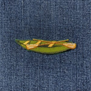May include: Embroidered patch featuring a green canoe with two crossed yellow oars. The patch is set against a blue denim background, creating a contrast of colors and textures. The design is detailed and appears to be machine-embroidered.