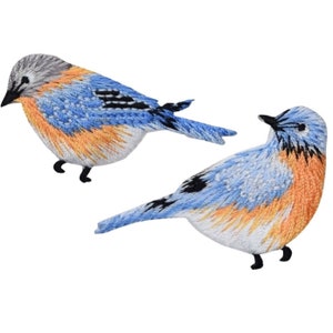 May include: Two embroidered patches of bluebirds. The birds have blue, orange, and gray plumage with black beaks and feet. The patches are detailed with intricate stitching, giving them a realistic appearance.