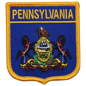 May include: Embroidered patch featuring the word "PENNSYLVANIA" in gold lettering above a detailed state seal. The seal includes a bald eagle, horses, and a shield, all set against a blue background with a gold border.