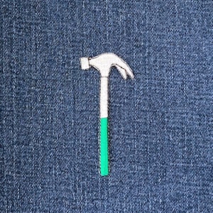 May include: Embroidered hammer patch with a white head, silver handle, and green lower handle. The patch is set against a blue denim background.