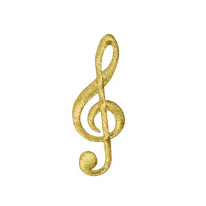 May include: A gold-coloured treble clef patch with a textured, embroidered appearance. The musical symbol is isolated against a white background. The patch is a decorative element for clothing or accessories.
