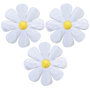 以下が含まれることがあります： 黄色の芯を持つ白いフェルトのデイジーの花のパッチが3つ。