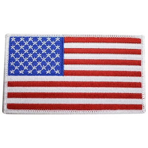 May include: Embroidered patch featuring the American flag. The patch has a blue field with white embroidered stars in the upper left corner and red and white stripes. The edges are finished with a white border.