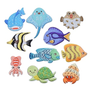May include: A selection of embroidered patches depicting marine life. The patches include a blue whale shark, a light blue stingray, a pufferfish, a yellow and black striped fish, a purple fish, a green fish, an orange fish, a pink octopus, a green turtle, and a crab.