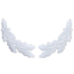 May include: Two white, embroidered leaf branch appliques. Each branch curves in a semi-circle, with detailed leaf shapes. The appliques are made of a soft, textured fabric, and are set against a plain white background.