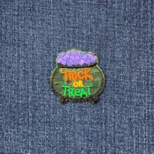 May include: A green cauldron with purple candy on top and the text "Trick or Treat" in orange and yellow letters.
