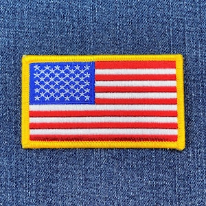 以下が含まれることがあります： 赤と白のストライプと青い星が刺繍されたアメリカの旗の黄色い縁取りのワッペンです。