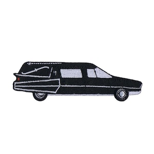 May include: An embroidered patch shaped like a black hearse with white window detailing, a white trim line along the body, and a small red accent on the rear tail light. The vehicle is depicted in a side profile view with two black wheels.